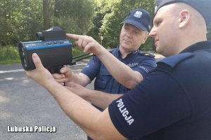 Starszy służbą policjant objaśnia młodszemu obsługę urządzenia pomiarowego Ultra Lyte.